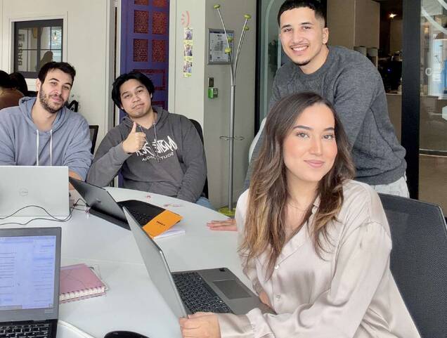 Photo des 4 membres de l'équipe d'étudiants souriants, travaillant sur le projet OseIA autour d'une table, devant leurs ordinateurs portables.