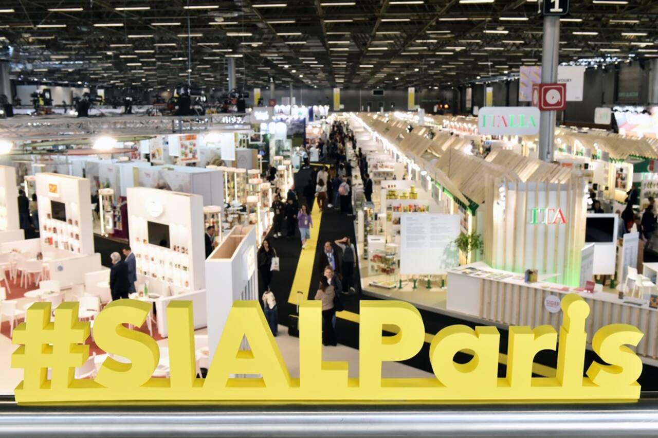 salon-comexposium-1-BD Photo du salon SIAL Paris en plan large avec les stands et les lettres jaune #SIALParis au premier plan